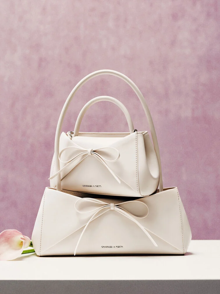Cream bow-detail top-handle and shoulder bags, a stylish gift idea for the festive season.