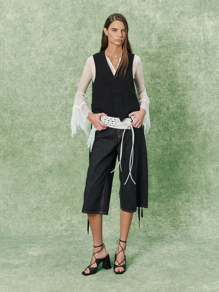 Strappy heeled sandals paired with jorts and a draped top, finished with a black vest.