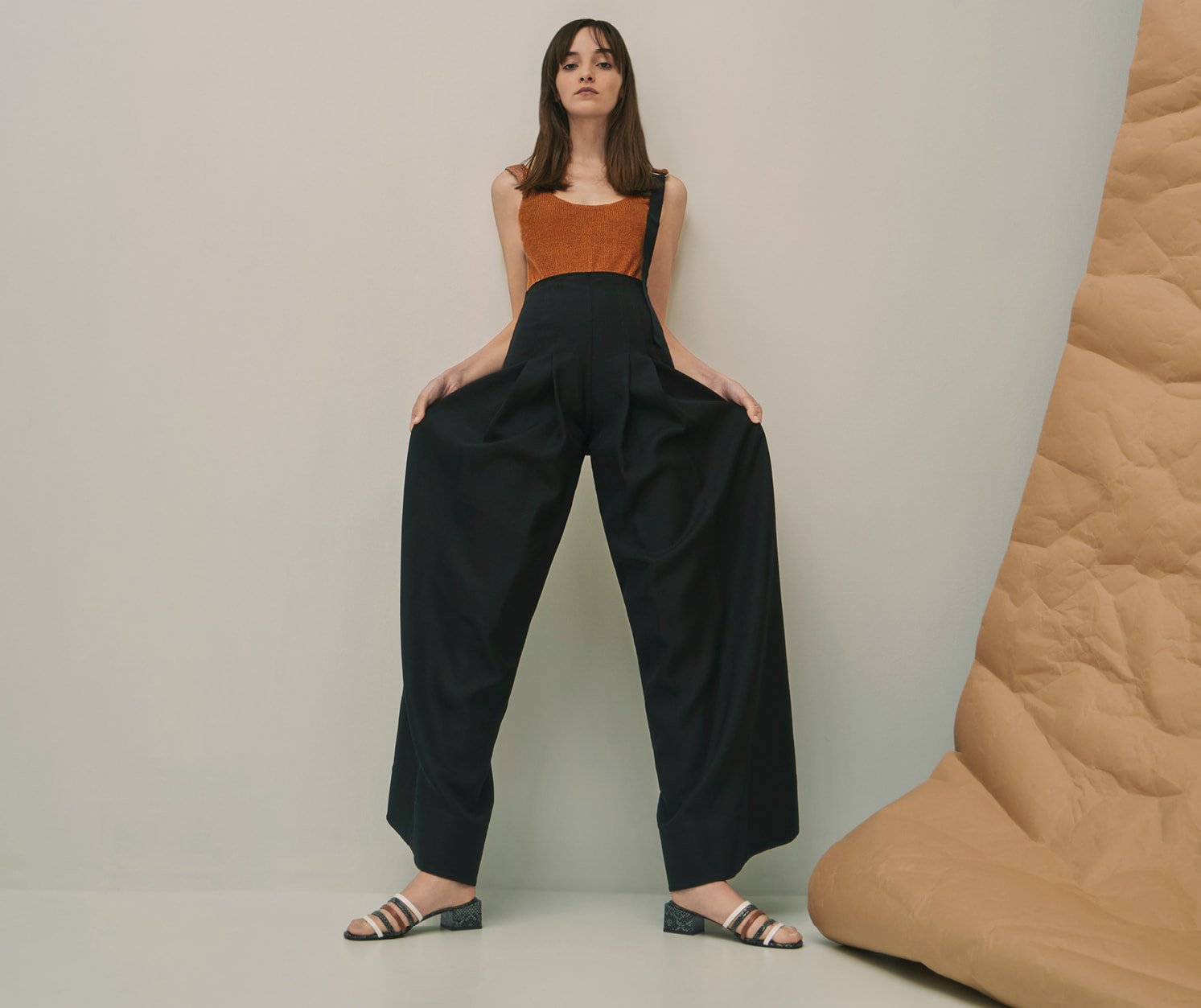 A model wearing wide-legged pants with snake print strappy mules.