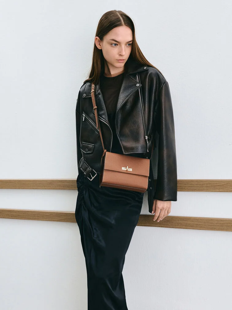 A crossbody bag with the strap worn diagonally across torso and the bag resting on the hip
