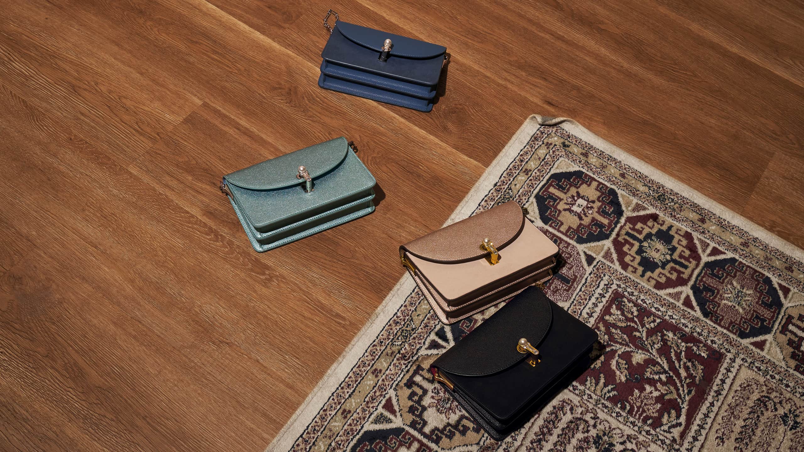 A flat lay of turn-lock clutches in black, blue, light blue and nude – CHARLES & KEITH