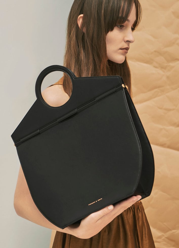 A model carrying an oversized geometric tote bag on her arms