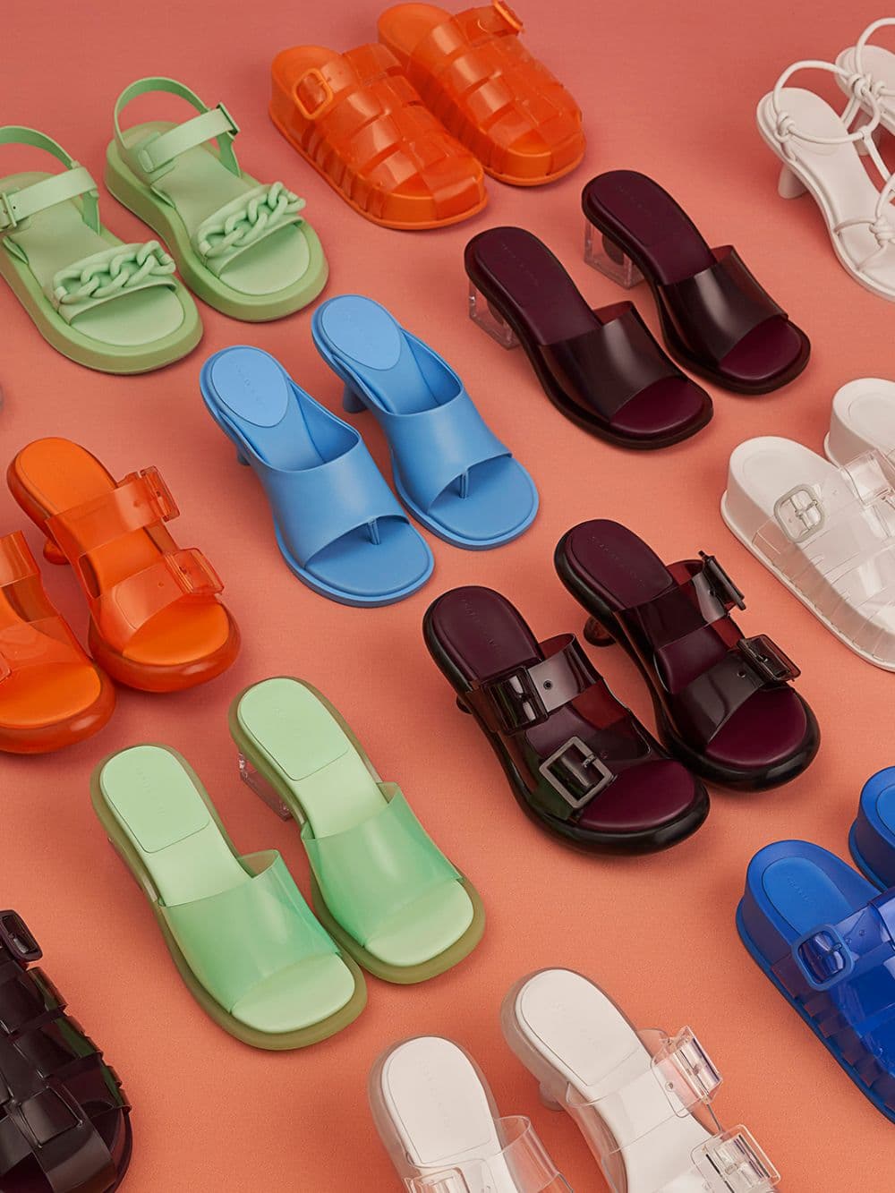 Women’s green and purple Madison clear sculptural heel mules; orange, purple, white and blue Madison caged see-through slide sandals; orange and purple Madison double buckle see-through mules; blue Alma thong mules; white Alma strappy knotted thong sandals; and green chunky chain-link ankle-strap padded sandals – CHARLES & KEITH