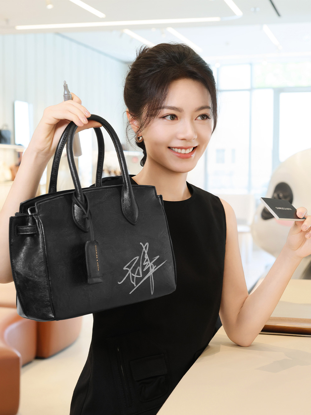 Zhao Jinmai poses with the Ginevra tote bag, which she had just autographed - CHARLES & KEITH