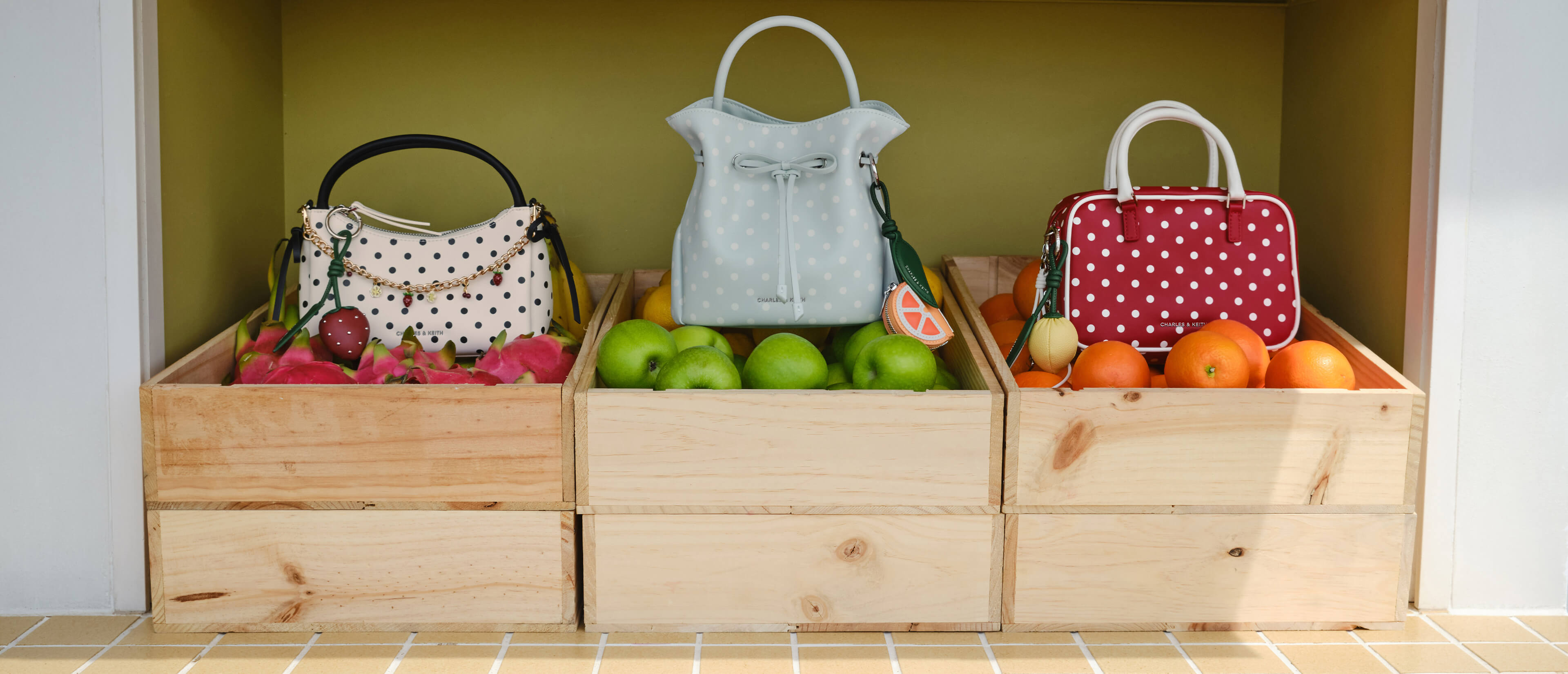 Hazel Polka-Dot Bow Top Handle Bag in cream with Strawberry Charm; Hazel Polka-Dot Bow Bucket Bag in sea-salt blue with Orange Slice Charm; Sianna Polka-Dot Bowling Bag in red with Lemon Charm - CHARLES & KEITH