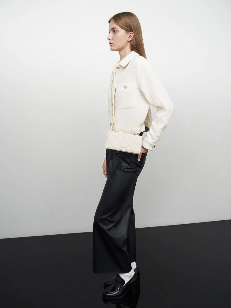 Um casaco creme combinado com calças de alfaiataria pretas e mocasins pretos para um visual em preto e branco marcante.