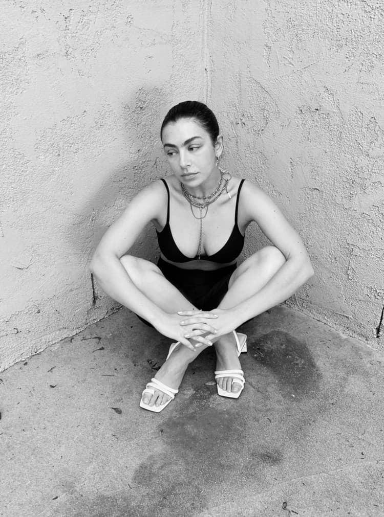 Charli XCX in CHARLES & KEITH’s toe-loop strappy slingback heels – sitting cross-legged