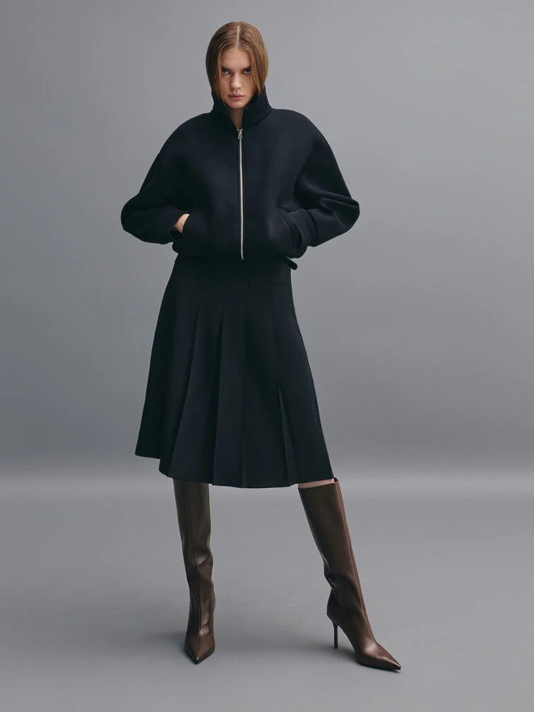 Dark-brown pointed-toe stiletto knee-high boots styled with a bomber jacket and a midi skirt.