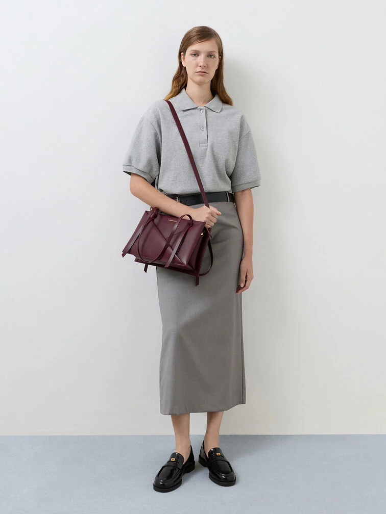 A sleek and structured crossbody bag styled with a midi skirt and collared top for an office-ready look.