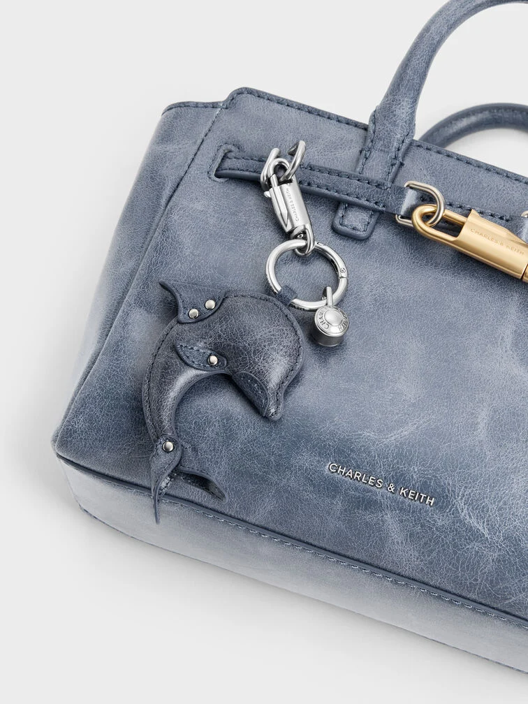 A blue dolphin bag charm attached to a bag in a matching blue hue.