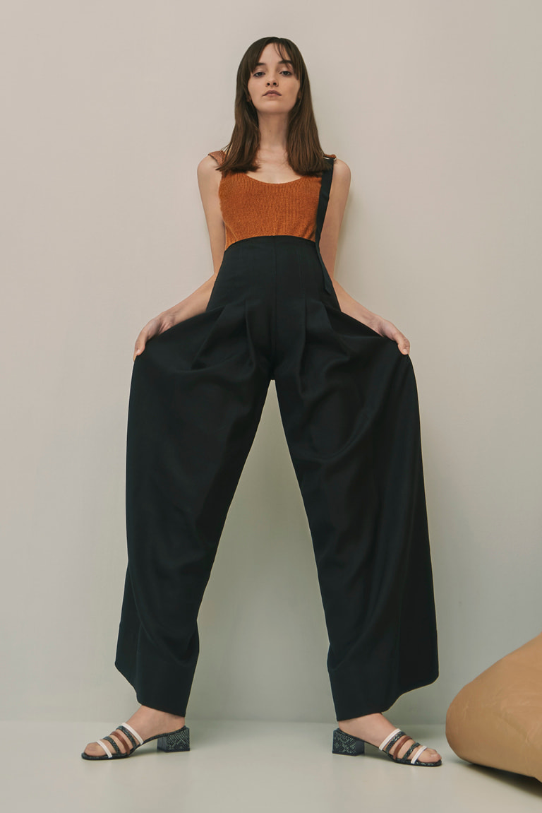 A model wearing wide-legged pants with snake print strappy mules.